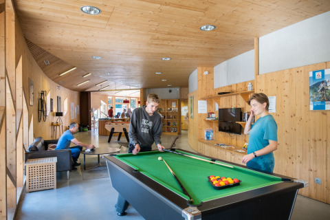 Personas juegan billar en un salón moderno de madera en Camping de Strasbourg, parque vacacional en Grand Est, Francia.