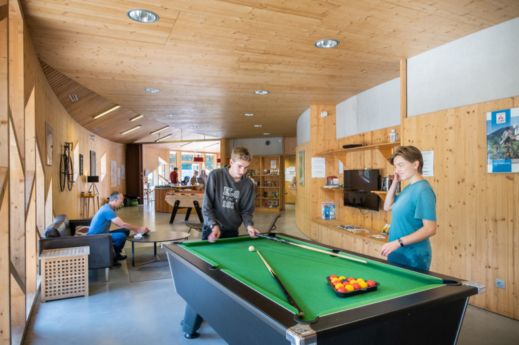 Menschen spielen Billard im modernen Gemeinschaftsraum mit Holzverkleidung im Camping de Strasbourg, Frankreich.