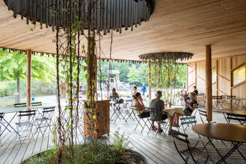 Udendørs caféområde med trædæk og planter på Camping de Strasbourg feriepark, Grand Est, Frankrig.