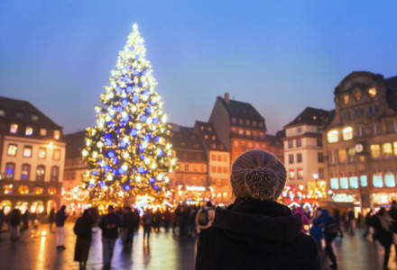 Persona observa un gran árbol de Navidad en una plaza iluminada en Estrasburgo, Grand Est, Francia al anochecer.