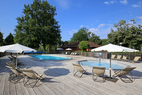 Zona de piscina al aire libre con tumbonas y sombrillas en Camping de l'Ill - Colmar, un parque vacacional en Grand Est, Francia.