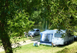 Campingplatz mit Wohnwagen, Auto und entspannten Campern am Fluss bei Camping de l'Ill - Colmar, Frankreich.