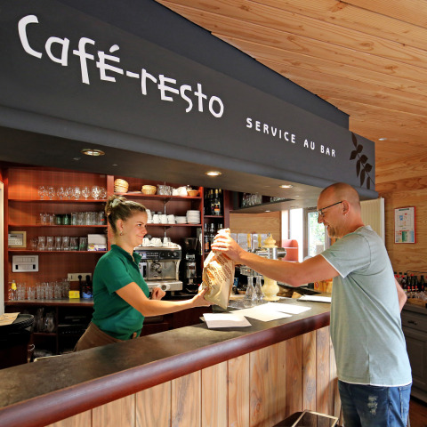 Gæst modtager mad fra personale ved café-restauranten på Camping de l'Ill - Colmar i Grand Est, Frankrig.