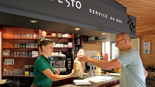 Cliente recibe comida del personal en la cafetería de Camping de l'Ill - Colmar en Grand Est, Francia.