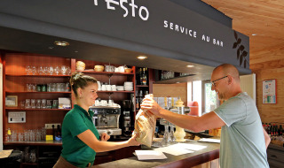 Cliente recibe comida del personal en la cafetería de Camping de l'Ill - Colmar en Grand Est, Francia.