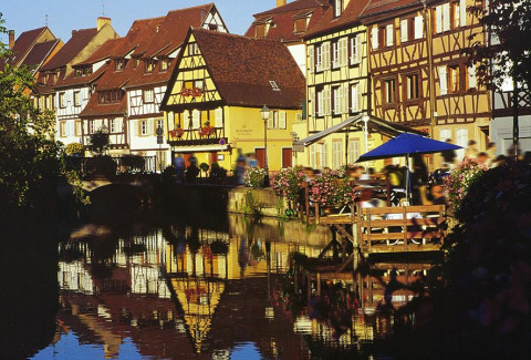 Maisons alsaciennes colorées et canal fleuri près de Horbourg-Wihr, Grand Est, France, au soleil.