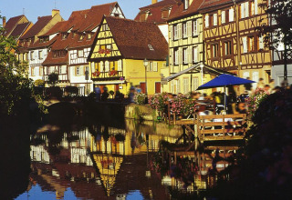 Colorful half-timbered houses and a canal scene near Horbourg-Wihr, Grand Est, France in sunlight.