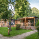 Træhytter i skovområde med grønne træer og græs, set ved Chalet Evasion på en solrig dag