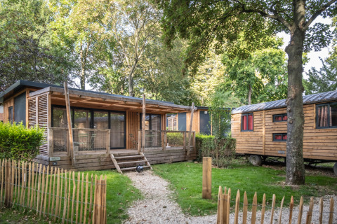 Vista esterna dello Chalet Evasion e roulotte tra gli alberi al Camping de Paris in Francia.