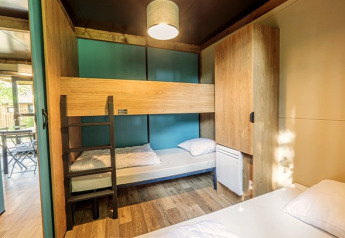 Chambre de glamping au Chalet Evasion avec lits superposés, armoires en bois et décoration moderne.
