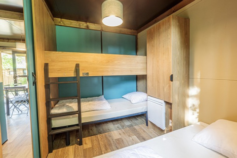 Glampingværelse i Chalet Evasion med køjeseng, træskabe og naturligt lys, moderne interiør.