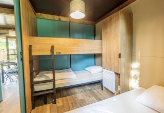 Chalet Evasion glampingruimte met houten stapelbedden, kasten en veel licht, modern interieur.
