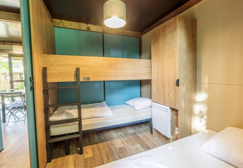 Chalet Evasion glampingruimte met houten stapelbedden, kasten en veel licht, modern interieur.