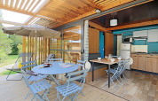 Chalet Evasion met moderne keuken, eetplaats binnen en terras met stoelen en parasol buiten.