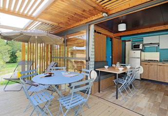 Udendørs og indendørs udsigt fra Chalet Evasion med spiseplads, terrasse og moderne køkkenområde.