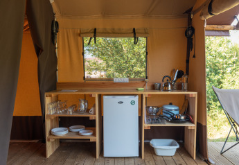 Coin cuisine sous tente Bungalow Classic au Camping de Strasbourg, France, avec étagères ouvertes et fenêtre.