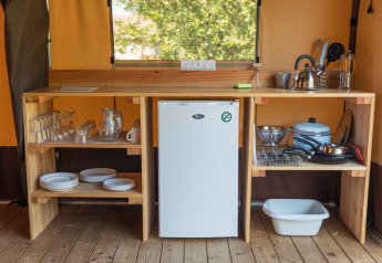 Pequeña cocina en una tienda Toile&bois Classic en Camping de Strasbourg con nevera, vajilla y utensilios.