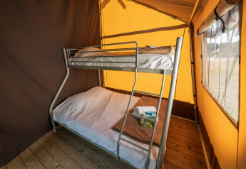 Intérieur d'une tente safari Toile&bois Classic au Camping de Strasbourg, avec un lit superposé et plancher bois.
