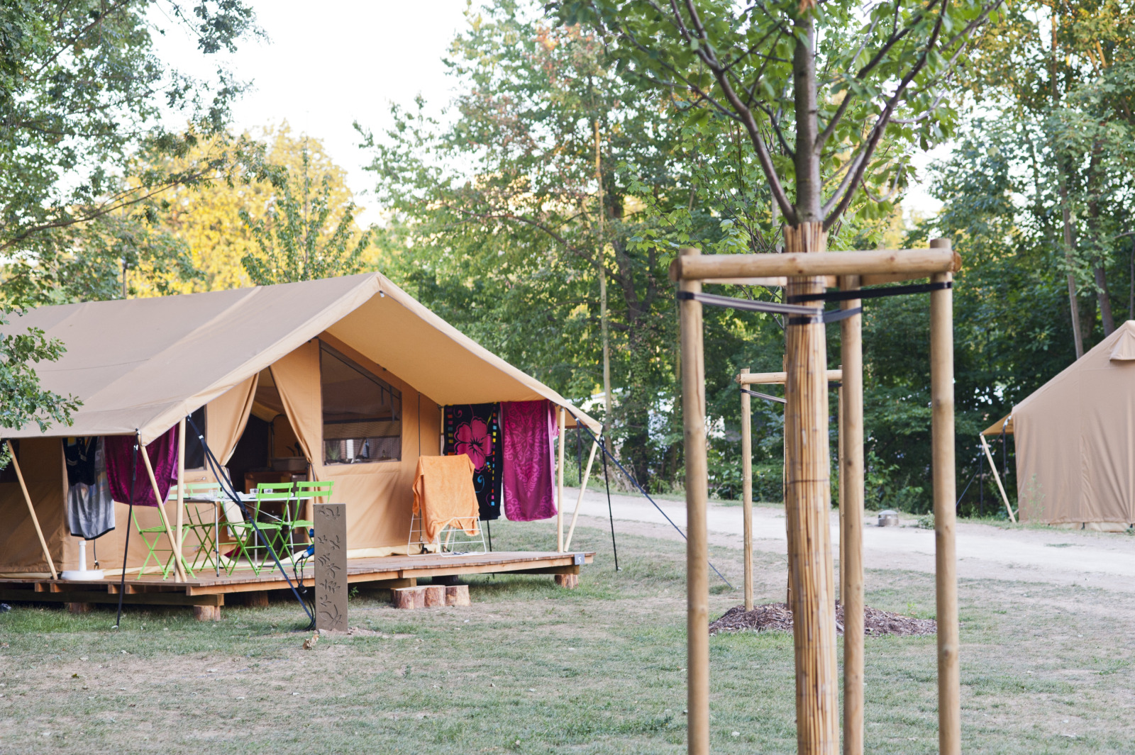 Safari tent Toile&bois Classic op Camping de Strasbourg in Frankrijk, met bomen en buitenmeubilair erbij.