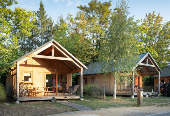 Cabañas de madera en Chalet Montana rodeadas de árboles, ideales para vacaciones en plena naturaleza.