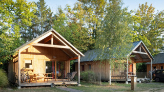 Cabañas de madera en Chalet Montana rodeadas de árboles, ideales para vacaciones en plena naturaleza.