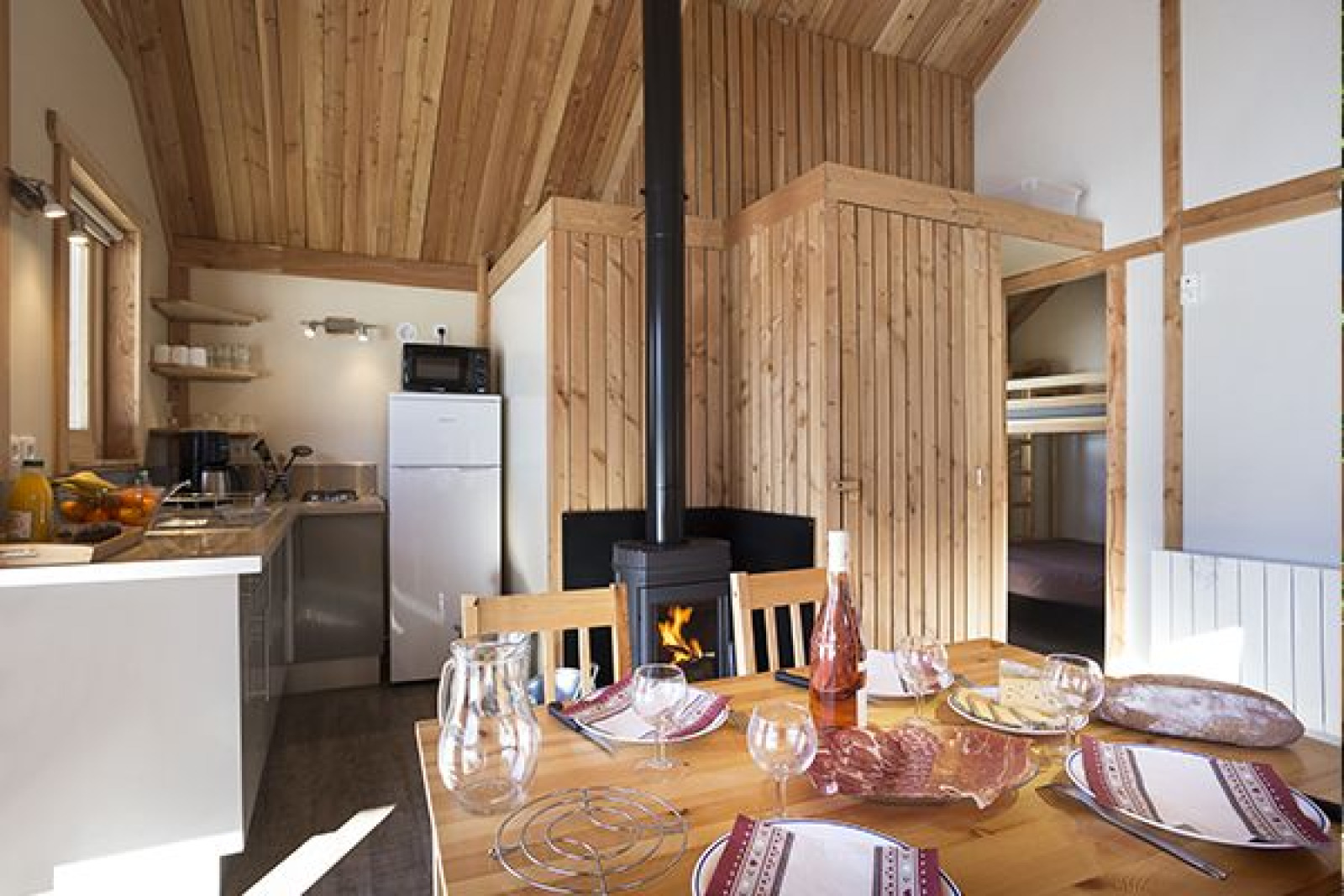 Interieur van de Chalet Montana op Camping de Strasbourg in Frankrijk met eettafel, kitchenette en houtkachel.
