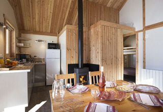Interior de la cabaña Chalet Montana en Camping de Strasbourg, Francia, con mesa de comedor, cocina y estufa.