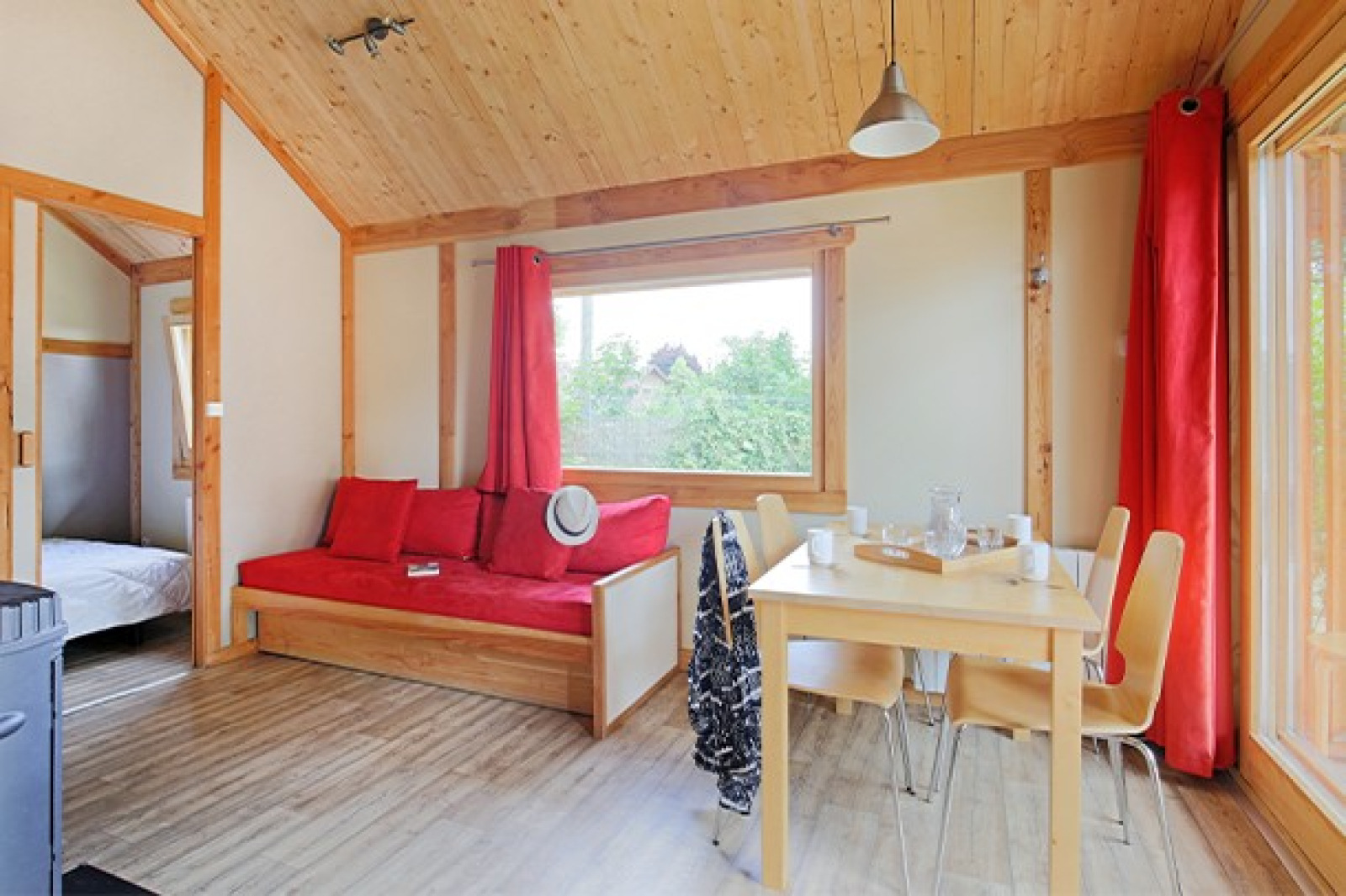 Licht en gezellig interieur van Chalet Montana op Camping de Strasbourg, Frankrijk, met hout en rode accenten.