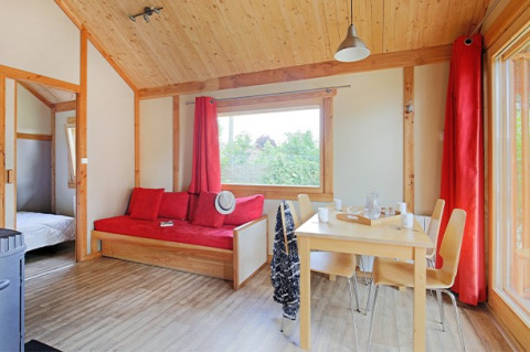 Luminoso y acogedor interior del Chalet Montana en Camping de Strasbourg, Francia, con madera y detalles rojos.