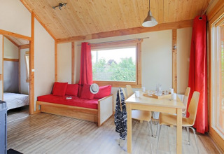 Luminoso y acogedor interior del Chalet Montana en Camping de Strasbourg, Francia, con madera y detalles rojos.
