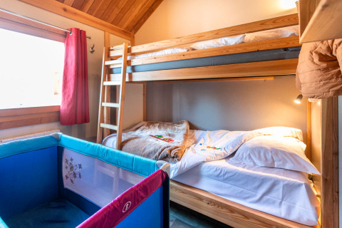 Habitación con litera de madera y cuna, Chalet Montana en Camping de Strasbourg, Francia.