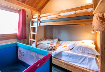 Chambre avec lits superposés en bois et lit bébé, Chalet Montana, Camping de Strasbourg, France.