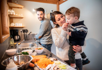 Famille cuisinant ensemble dans la cuisine du Chalet Montana au Camping de Strasbourg, France.