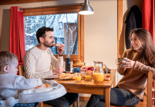 Familia desayunando junta en una cabaña con vista nevada en Chalet Montana, Camping de Strasbourg, Francia.