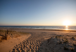 Solnedgang over et fredeligt sandstrand nær Saint-Michel-Escalus, Nouvelle-Aquitaine, Frankrig.