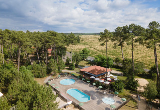 Vakantiepark Huttopia Landes Sud in Nouvelle-Aquitaine, Frankrijk met zwembad en terras omringd door bos.