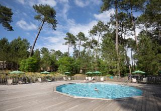 Svømmepøl omringet af fyrretræer og liggestole på Huttopia Landes Sud feriepark i Nouvelle-Aquitaine, Frankrig.