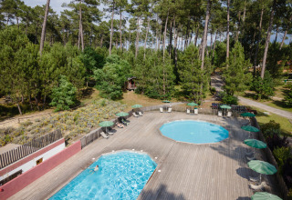 Udsigt over to swimmingpools og liggestole omgivet af skov ved Huttopia Landes Sud i Nouvelle-Aquitaine.
