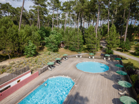 Vista aérea de dos piscinas rodeadas de tumbonas y pinos en Huttopia Landes Sud, Nouvelle-Aquitaine, Francia.