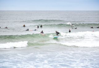 Surfere fanger bølger nær Saint-Michel-Escalus i Nouvelle-Aquitaine, Frankrig, under en overskyet dag.