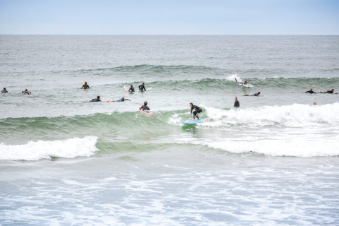 Surfers pakken golven bij Saint-Michel-Escalus, Nouvelle-Aquitaine, Frankrijk, op een bewolkte stranddag.