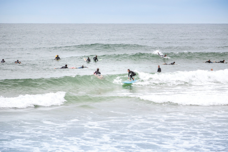 Surfers riding waves near Saint-Michel-Escalus, Nouvelle-Aquitaine, France, on a cloudy day at the beach.