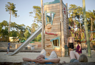 Børn leger på legeplads med klatretårn og rutsjebane i ferieparken Huttopia Landes Sud i Frankrig.