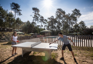 To personer spiller bordtennis udendørs på Huttopia Landes Sud feriepark i Nouvelle-Aquitaine, Frankrig.
