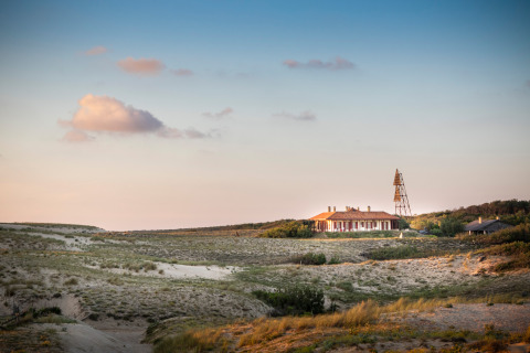 Una casa tra dune sabbiose al tramonto vicino a Saint-Michel-Escalus, Nouvelle-Aquitaine, Francia.
