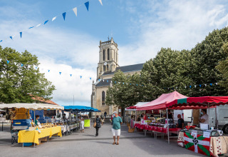 Marktstände und Menschen vor einer Kirche in Saint-Michel-Escalus, Nouvelle-Aquitaine, Frankreich.