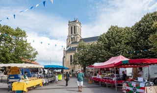 Puestos de mercado y personas frente a una iglesia en Saint-Michel-Escalus, Nouvelle-Aquitania, Francia.