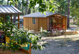 Udsigt til Chalet Evasion-hytte med cykler og siddeplads udenfor i Huttopia Landes Sud, Frankrig.