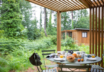 Desayuno al aire libre en la terraza del Chalet Ottawa en Huttopia Landes Sud, rodeado de bosque en Francia.