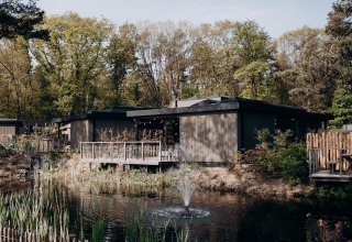 Luxury Family Water Lodge con jacuzzi en Soof Retreats, Países Bajos, junto a estanque y bosque verde.